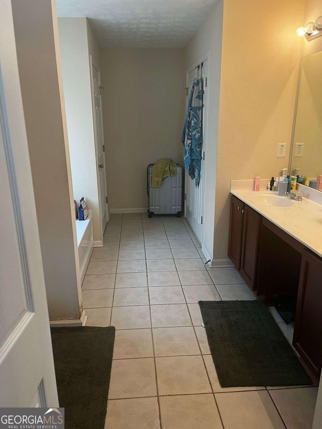 bathroom with tile patterned floors, vanity, baseboards, and a bath