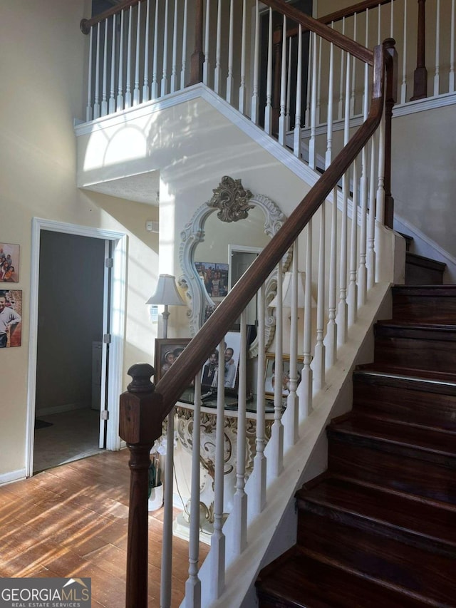stairs with baseboards, a high ceiling, and wood finished floors
