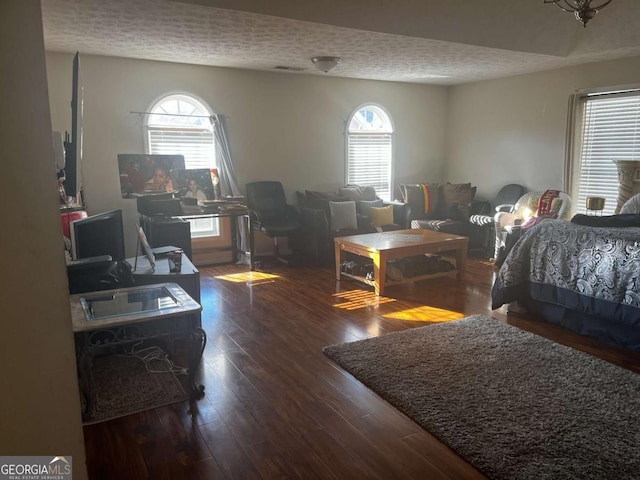 bedroom with multiple windows, wood finished floors, and a textured ceiling