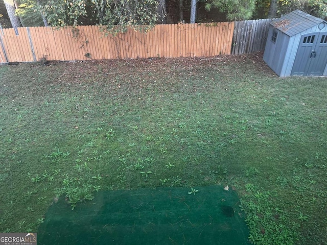view of yard with an outbuilding, a storage unit, and fence private yard