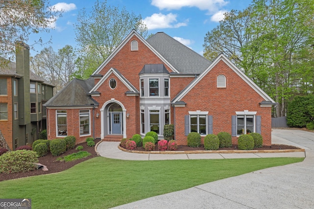 view of front of home featuring brick siding, a shingled roof, and a front lawn