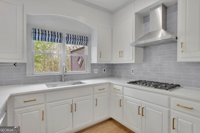 kitchen featuring a sink, decorative backsplash, wall chimney range hood, and stainless steel gas stovetop