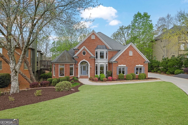 view of front of home featuring brick siding, roof with shingles, and a front lawn