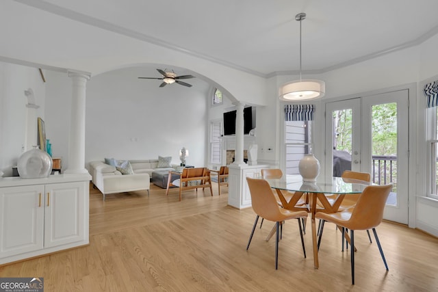 dining space with ornate columns, arched walkways, light wood-style floors, and a ceiling fan