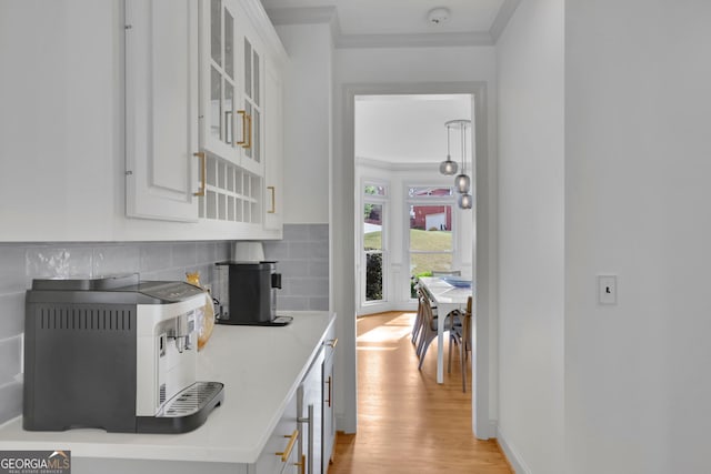 kitchen featuring ornamental molding, white cabinets, tasteful backsplash, and light wood-type flooring