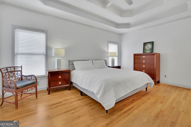 bedroom featuring light wood-style floors, ornamental molding, and a raised ceiling