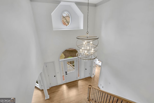 foyer featuring a wealth of natural light, wood finished floors, a chandelier, and a towering ceiling