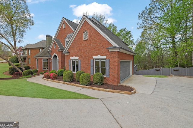 traditional home featuring fence, driveway, a front lawn, brick siding, and a garage