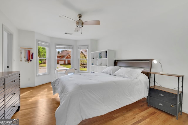 bedroom with a ceiling fan, baseboards, light wood finished floors, and visible vents