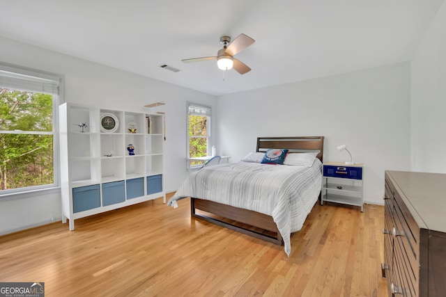 bedroom with light wood-style flooring, visible vents, and a ceiling fan