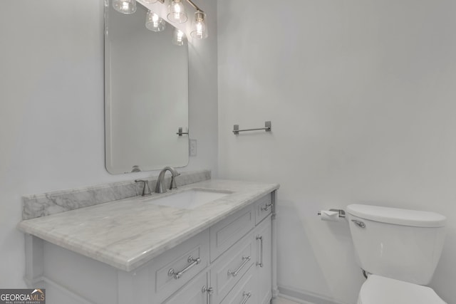 bathroom featuring toilet, vanity, and baseboards