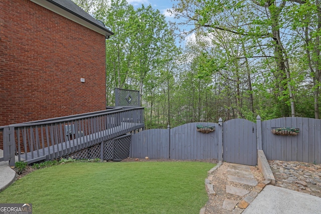 view of yard featuring a gate, fence, and a wooden deck