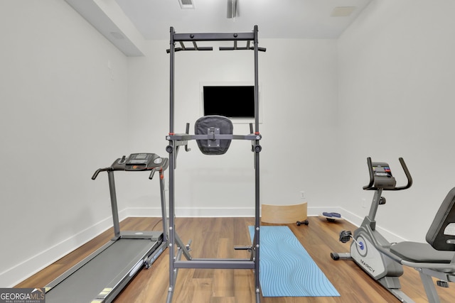 exercise area with baseboards, visible vents, and wood finished floors