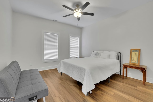 bedroom with light wood finished floors, baseboards, visible vents, and ceiling fan
