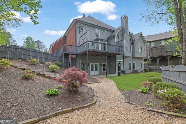 rear view of house featuring a gate, a fenced backyard, a deck, and a yard