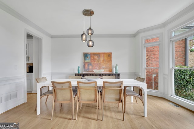 dining area with light wood finished floors, wainscoting, crown molding, and visible vents