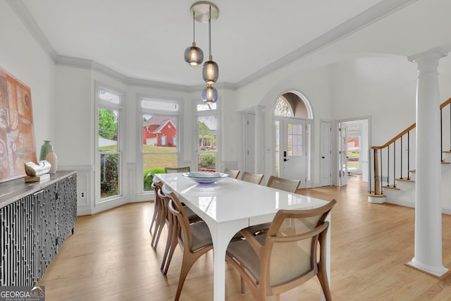 dining area with stairs, crown molding, light wood-style flooring, and ornate columns