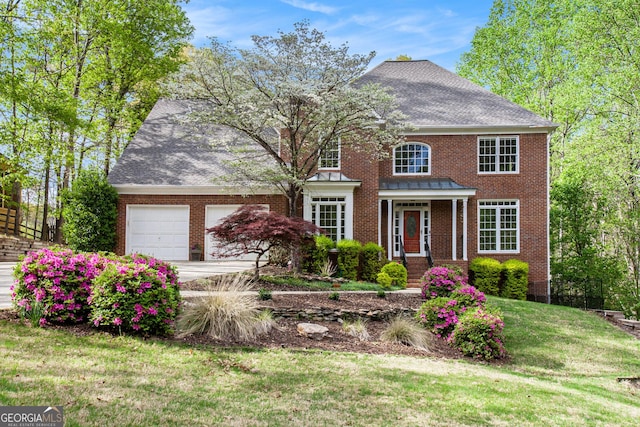 view of front facade featuring roof with shingles, a front yard, brick siding, a garage, and concrete driveway