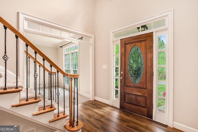foyer entrance with wood finished floors, baseboards, and stairway