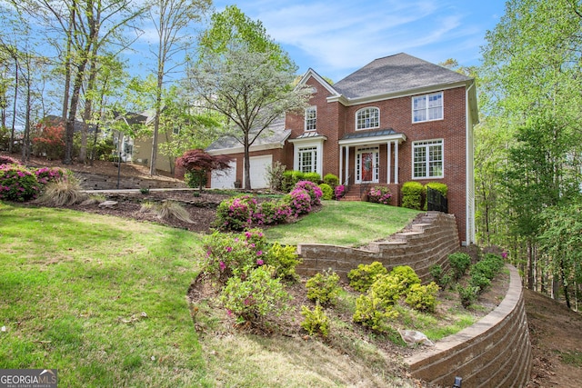 colonial-style house with a garage, brick siding, and a front lawn