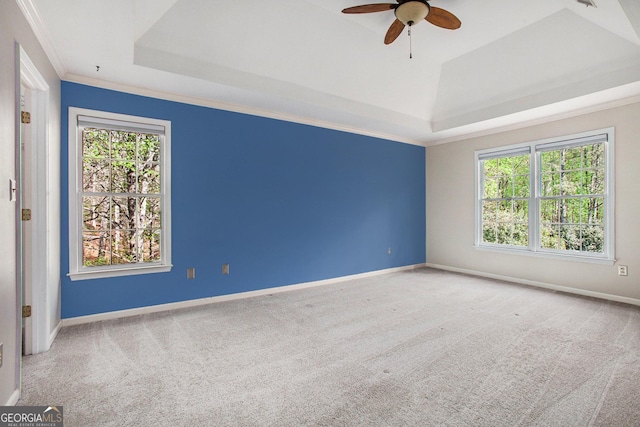 empty room with baseboards, ornamental molding, a raised ceiling, carpet floors, and ceiling fan