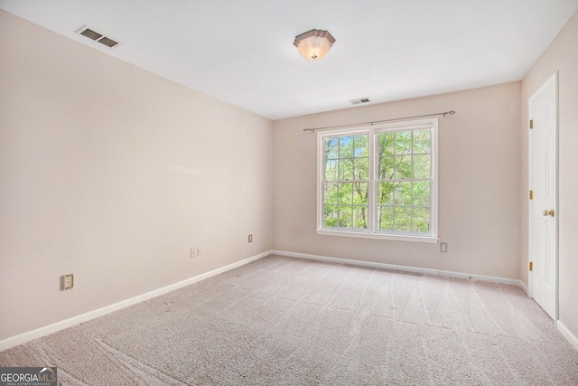 carpeted spare room featuring baseboards and visible vents