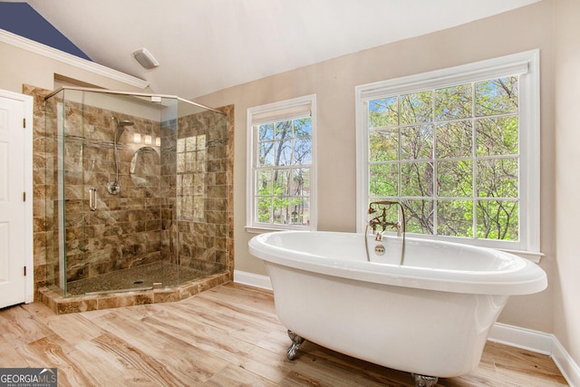 bathroom featuring baseboards, a soaking tub, a shower stall, vaulted ceiling, and wood finished floors