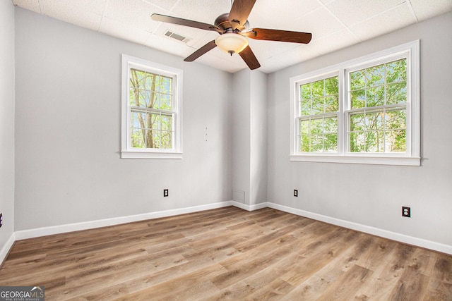 spare room with visible vents, a wealth of natural light, ceiling fan, and wood finished floors