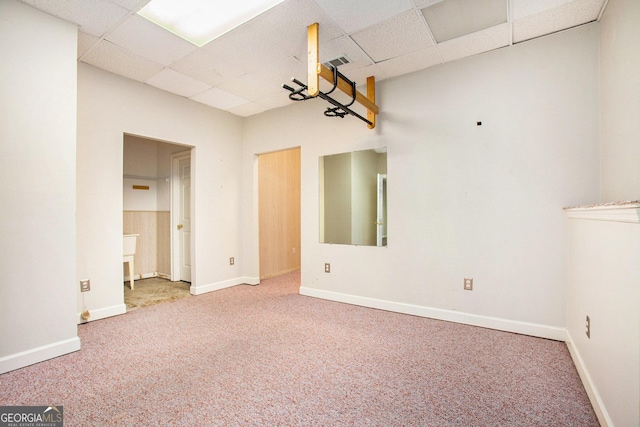carpeted spare room with visible vents, a drop ceiling, and baseboards