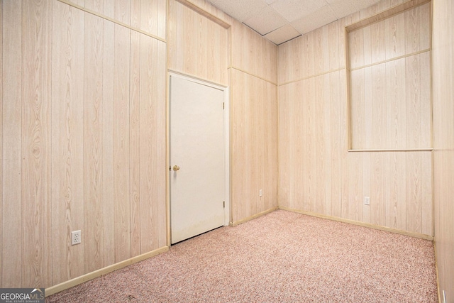 unfurnished room with wooden walls, carpet floors, and a paneled ceiling