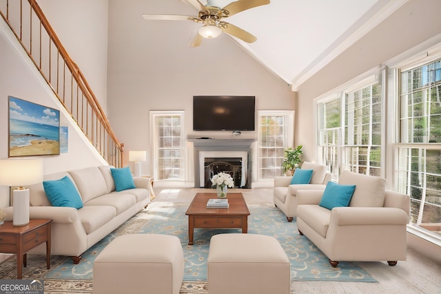 living room with ornamental molding, ceiling fan, high vaulted ceiling, and stairs