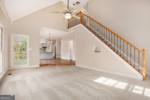 unfurnished living room featuring high vaulted ceiling, carpet flooring, ornamental molding, and ceiling fan