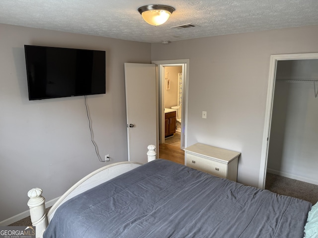 carpeted bedroom with baseboards, a textured ceiling, visible vents, and a closet