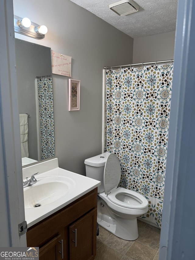 full bath with vanity, toilet, a textured ceiling, visible vents, and curtained shower