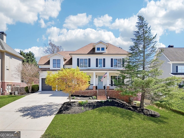 american foursquare style home featuring cooling unit, an attached garage, driveway, a front lawn, and covered porch