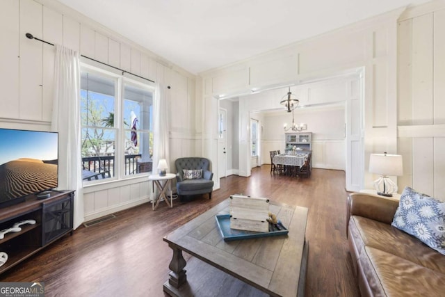 living room featuring a decorative wall, wood finished floors, and an inviting chandelier