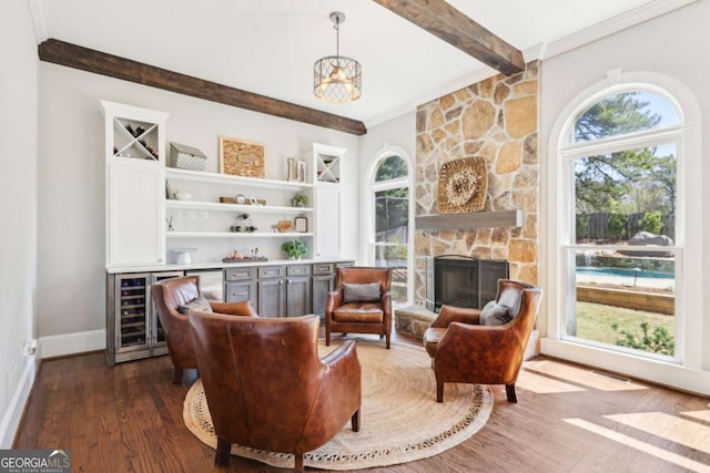 living area featuring dark wood-type flooring, beamed ceiling, a wealth of natural light, and a bar