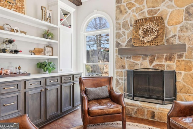 living area with a stone fireplace and wood finished floors