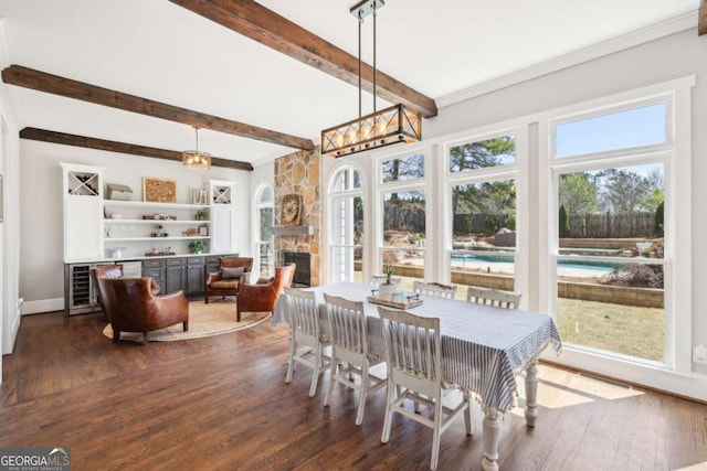 dining area featuring dark wood-style flooring, beam ceiling, and a healthy amount of sunlight