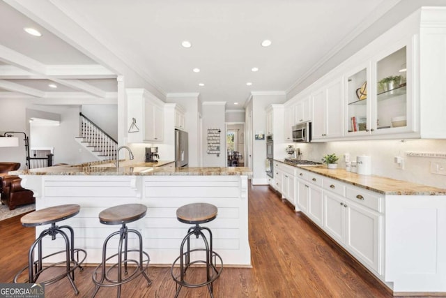 kitchen with dark wood-style floors, white cabinetry, stainless steel appliances, and a peninsula