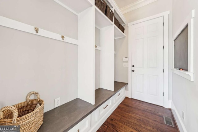 mudroom with visible vents, crown molding, and dark wood finished floors