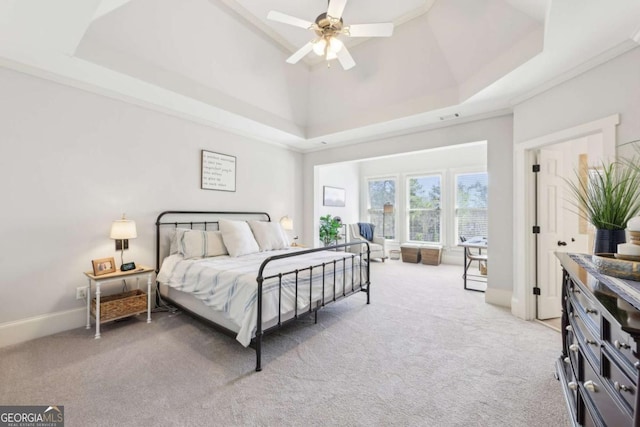 bedroom with a ceiling fan, a raised ceiling, baseboards, light colored carpet, and a towering ceiling