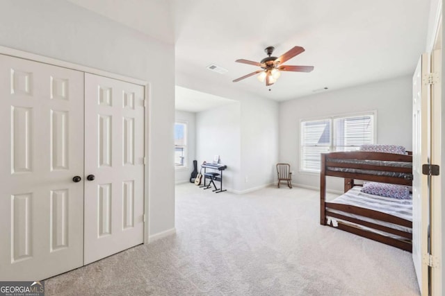 carpeted bedroom with a closet, baseboards, multiple windows, and visible vents