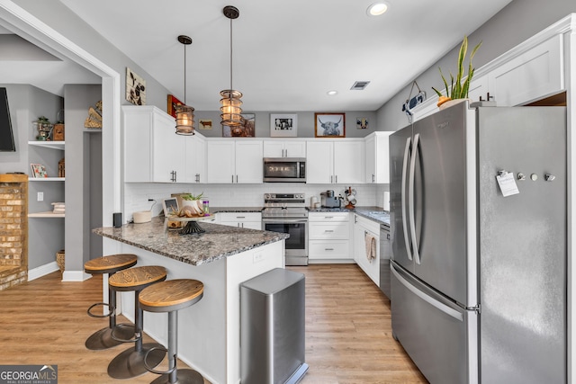 kitchen featuring visible vents, white cabinets, light wood-style flooring, and stainless steel appliances