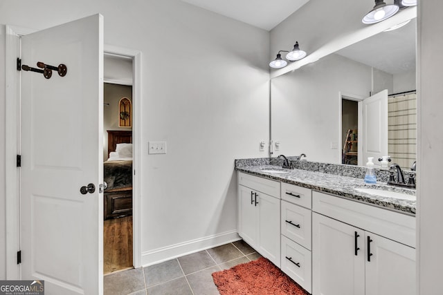 ensuite bathroom featuring connected bathroom, double vanity, tile patterned flooring, and a sink