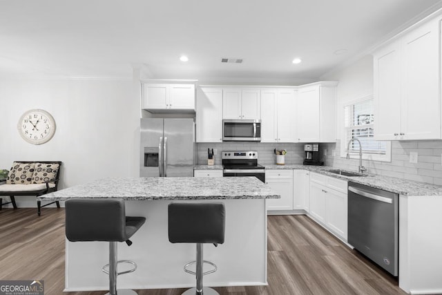 kitchen with a sink, white cabinetry, crown molding, a kitchen island, and appliances with stainless steel finishes