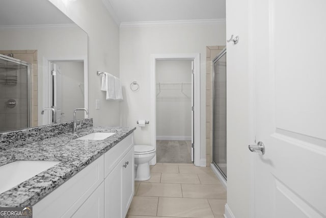 bathroom with a walk in closet, crown molding, a stall shower, and a sink