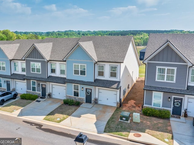 townhome / multi-family property with concrete driveway, stone siding, and board and batten siding