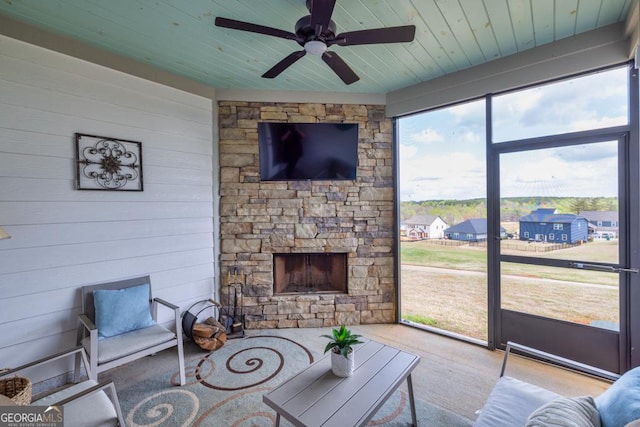 living room with wooden walls, wood finished floors, a ceiling fan, wood ceiling, and a fireplace