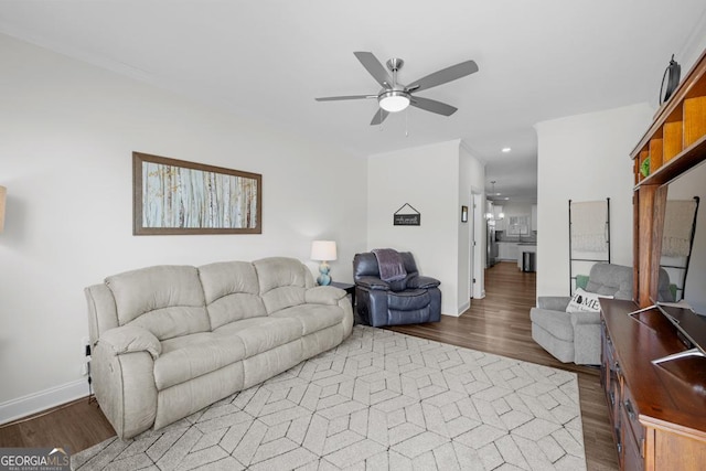 living room featuring a ceiling fan, wood finished floors, baseboards, ornamental molding, and recessed lighting